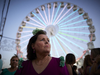 A woman is dressing in a typical flamenco dress and watching the swings at the fairgrounds during the festivities of the Corpus Christi in G...