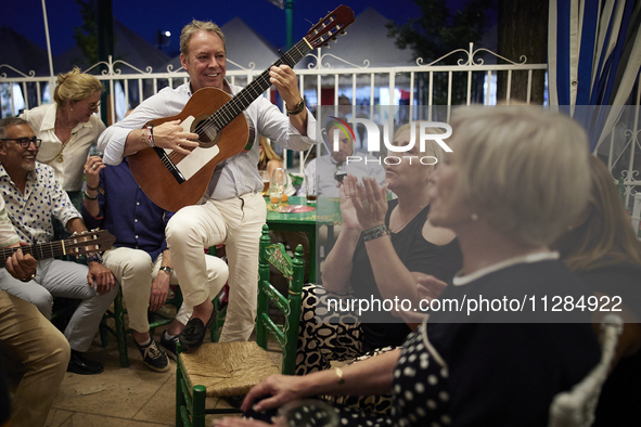 A man is playing the guitar in a circle with people who are clapping to the rhythm during the festivities of the Corpus Christi in Granada,...