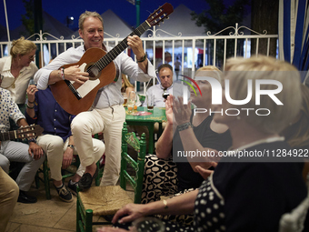 A man is playing the guitar in a circle with people who are clapping to the rhythm during the festivities of the Corpus Christi in Granada,...