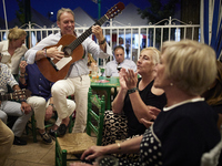 A man is playing the guitar in a circle with people who are clapping to the rhythm during the festivities of the Corpus Christi in Granada,...