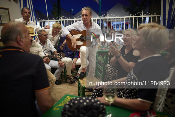 A man is playing the guitar in a circle with people who are clapping to the rhythm during the festivities of the Corpus Christi in Granada,...