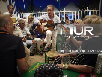 A man is playing the guitar in a circle with people who are clapping to the rhythm during the festivities of the Corpus Christi in Granada,...