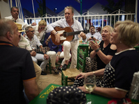 A man is playing the guitar in a circle with people who are clapping to the rhythm during the festivities of the Corpus Christi in Granada,...