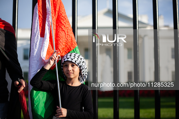 A young girl holds a Palestinian flag in front of the White House where she is taking part in a protest against the Israeli attacks on civil...