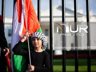 A young girl holds a Palestinian flag in front of the White House where she is taking part in a protest against the Israeli attacks on civil...