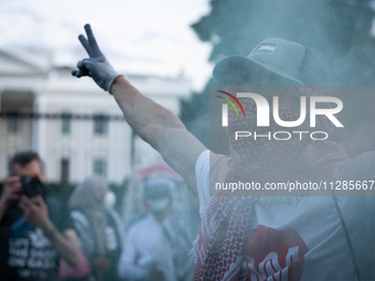 A demonstrator stands in front of a green smoke canister in front of the White House during a protest against the Israeli attacks on civilia...