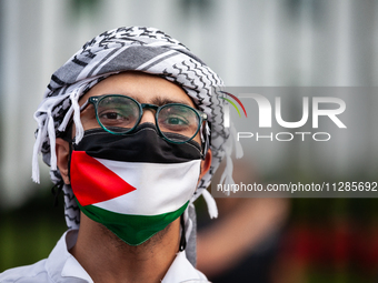 A demonstrator in a keffiyeh and Palestinian flag participates in a protest at the White House against the Israeli attacks on civilians in R...