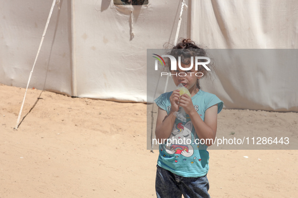 A Palestinian girl is eating ice cream at a camp for displaced Palestinians in Deir el-Balah in the central Gaza Strip on May 29, 2024, amid...