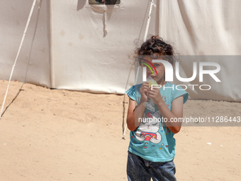 A Palestinian girl is eating ice cream at a camp for displaced Palestinians in Deir el-Balah in the central Gaza Strip on May 29, 2024, amid...