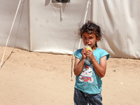 A Palestinian girl is eating ice cream at a camp for displaced Palestinians in Deir el-Balah in the central Gaza Strip on May 29, 2024, amid...