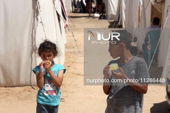 A Palestinian girl is eating ice cream at a camp for displaced Palestinians in Deir el-Balah in the central Gaza Strip on May 29, 2024, amid...