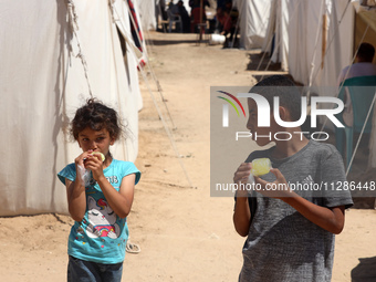 A Palestinian girl is eating ice cream at a camp for displaced Palestinians in Deir el-Balah in the central Gaza Strip on May 29, 2024, amid...