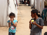 A Palestinian girl is eating ice cream at a camp for displaced Palestinians in Deir el-Balah in the central Gaza Strip on May 29, 2024, amid...