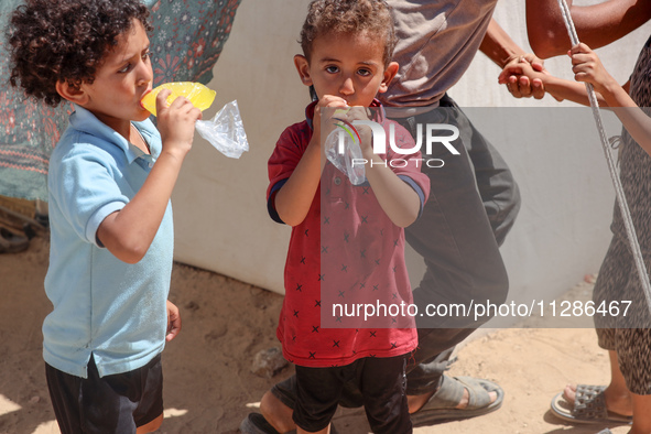 A Palestinian boy is eating ice cream at a camp for displaced Palestinians in Deir el-Balah in the central Gaza Strip on May 29, 2024, amid...