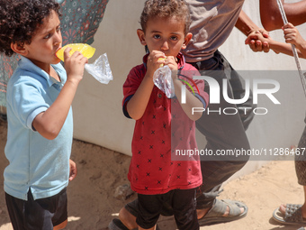 A Palestinian boy is eating ice cream at a camp for displaced Palestinians in Deir el-Balah in the central Gaza Strip on May 29, 2024, amid...