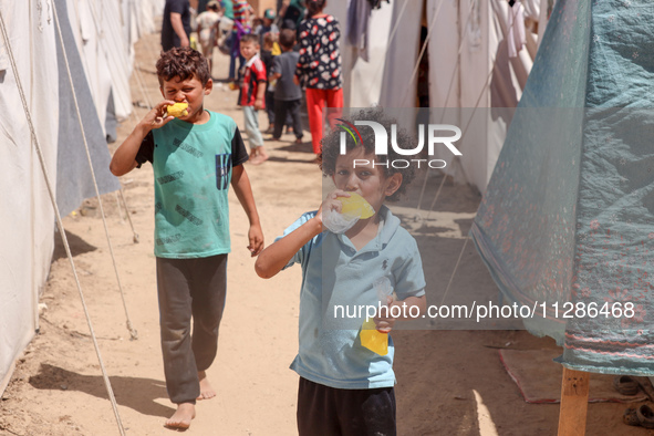 A Palestinian boy is eating ice cream at a camp for displaced Palestinians in Deir el-Balah in the central Gaza Strip on May 29, 2024, amid...