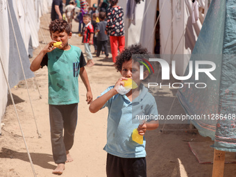 A Palestinian boy is eating ice cream at a camp for displaced Palestinians in Deir el-Balah in the central Gaza Strip on May 29, 2024, amid...