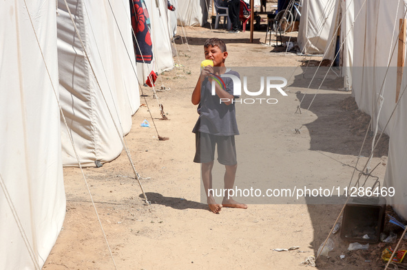 A Palestinian boy is eating ice cream at a camp for displaced Palestinians in Deir el-Balah in the central Gaza Strip on May 29, 2024, amid...