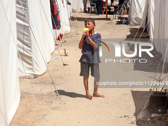 A Palestinian boy is eating ice cream at a camp for displaced Palestinians in Deir el-Balah in the central Gaza Strip on May 29, 2024, amid...