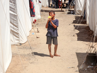 A Palestinian boy is eating ice cream at a camp for displaced Palestinians in Deir el-Balah in the central Gaza Strip on May 29, 2024, amid...