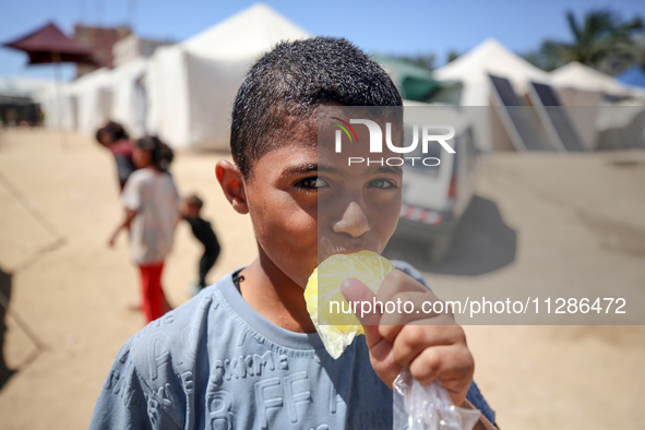 A Palestinian boy is eating ice cream at a camp for displaced Palestinians in Deir el-Balah in the central Gaza Strip on May 29, 2024, amid...