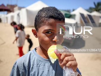 A Palestinian boy is eating ice cream at a camp for displaced Palestinians in Deir el-Balah in the central Gaza Strip on May 29, 2024, amid...