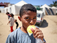 A Palestinian boy is eating ice cream at a camp for displaced Palestinians in Deir el-Balah in the central Gaza Strip on May 29, 2024, amid...