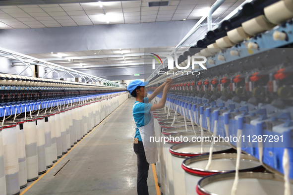 A worker is performing textile work at a textile workshop of a textile company in Aksu prefecture, Northwest China's Xinjiang Uygur autonomo...