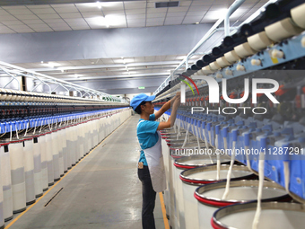 A worker is performing textile work at a textile workshop of a textile company in Aksu prefecture, Northwest China's Xinjiang Uygur autonomo...