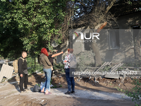 People are standing by a house damaged by the overnight Russian missile attack in the Novobavarskyi district of Kharkiv, Ukraine, on May 31,...