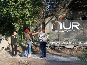 People are standing by a house damaged by the overnight Russian missile attack in the Novobavarskyi district of Kharkiv, Ukraine, on May 31,...