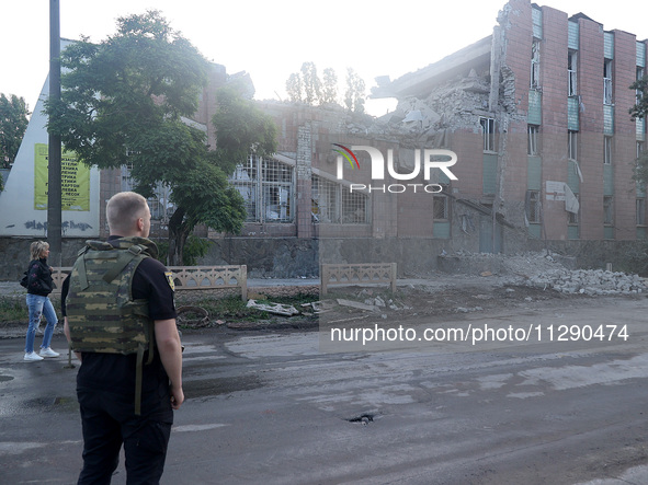 A law enforcer in a bulletproof vest is facing a building damaged by the overnight Russian missile attack in the Novobavarskyi district of K...