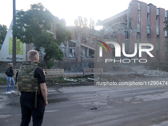 A law enforcer in a bulletproof vest is facing a building damaged by the overnight Russian missile attack in the Novobavarskyi district of K...