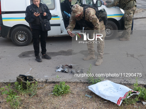 A law enforcer is taking pictures of missile debris after the overnight Russian missile attack in the Novobavarskyi district of Kharkiv, nor...