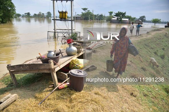 A flood-affected woman with her belongings is taking shelter in a higher place after the landfall of cyclone 'Remal', in Nagaon district of...