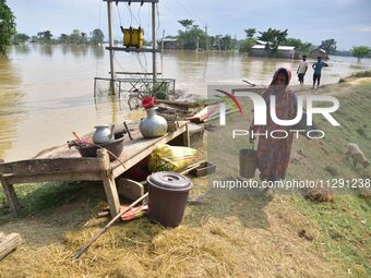 A flood-affected woman with her belongings is taking shelter in a higher place after the landfall of cyclone 'Remal', in Nagaon district of...