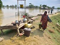 A flood-affected woman with her belongings is taking shelter in a higher place after the landfall of cyclone 'Remal', in Nagaon district of...