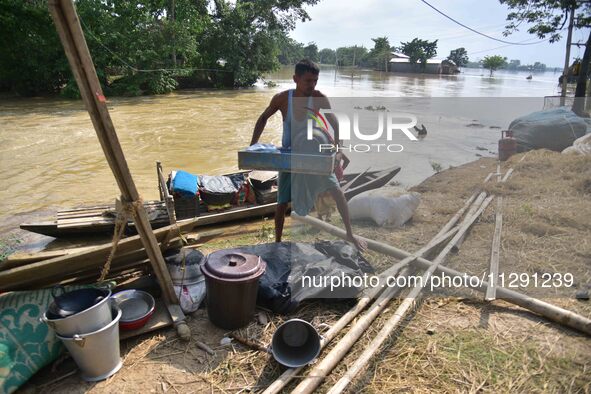 Flood-affected individuals are taking shelter with their belongings in a higher place after the landfall of cyclone 'Remal' in Nagaon distri...