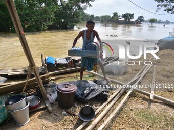 Flood-affected individuals are taking shelter with their belongings in a higher place after the landfall of cyclone 'Remal' in Nagaon distri...