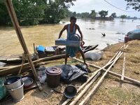 Flood-affected individuals are taking shelter with their belongings in a higher place after the landfall of cyclone 'Remal' in Nagaon distri...