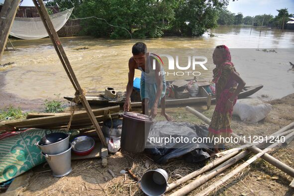 Flood-affected individuals are taking shelter with their belongings in a higher place after the landfall of cyclone 'Remal' in Nagaon distri...