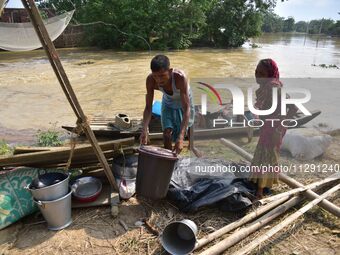 Flood-affected individuals are taking shelter with their belongings in a higher place after the landfall of cyclone 'Remal' in Nagaon distri...