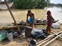 Flood-affected individuals are taking shelter with their belongings in a higher place after the landfall of cyclone 'Remal' in Nagaon distri...