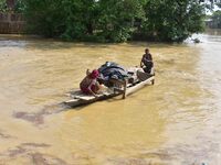 Villagers are taking their belongings on a boat to a safer place after the landfall of cyclone 'Remal' in Nagaon district of Assam, India, o...