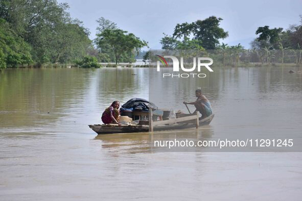 Villagers are taking their belongings on a boat to a safer place after the landfall of cyclone 'Remal' in Nagaon district of Assam, India, o...