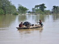 Villagers are taking their belongings on a boat to a safer place after the landfall of cyclone 'Remal' in Nagaon district of Assam, India, o...