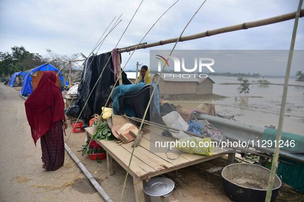 A flood-affected woman with her belongings is taking shelter in a higher place after the landfall of cyclone 'Remal', in Nagaon district of...