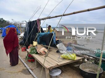 A flood-affected woman with her belongings is taking shelter in a higher place after the landfall of cyclone 'Remal', in Nagaon district of...