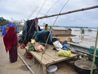 A flood-affected woman with her belongings is taking shelter in a higher place after the landfall of cyclone 'Remal', in Nagaon district of...