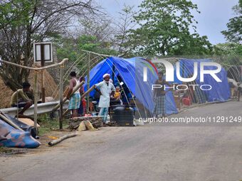 Flood-affected villagers are staying in their makeshift camp on a road after the landfall of cyclone 'Remal' in Nagaon district of Assam, In...